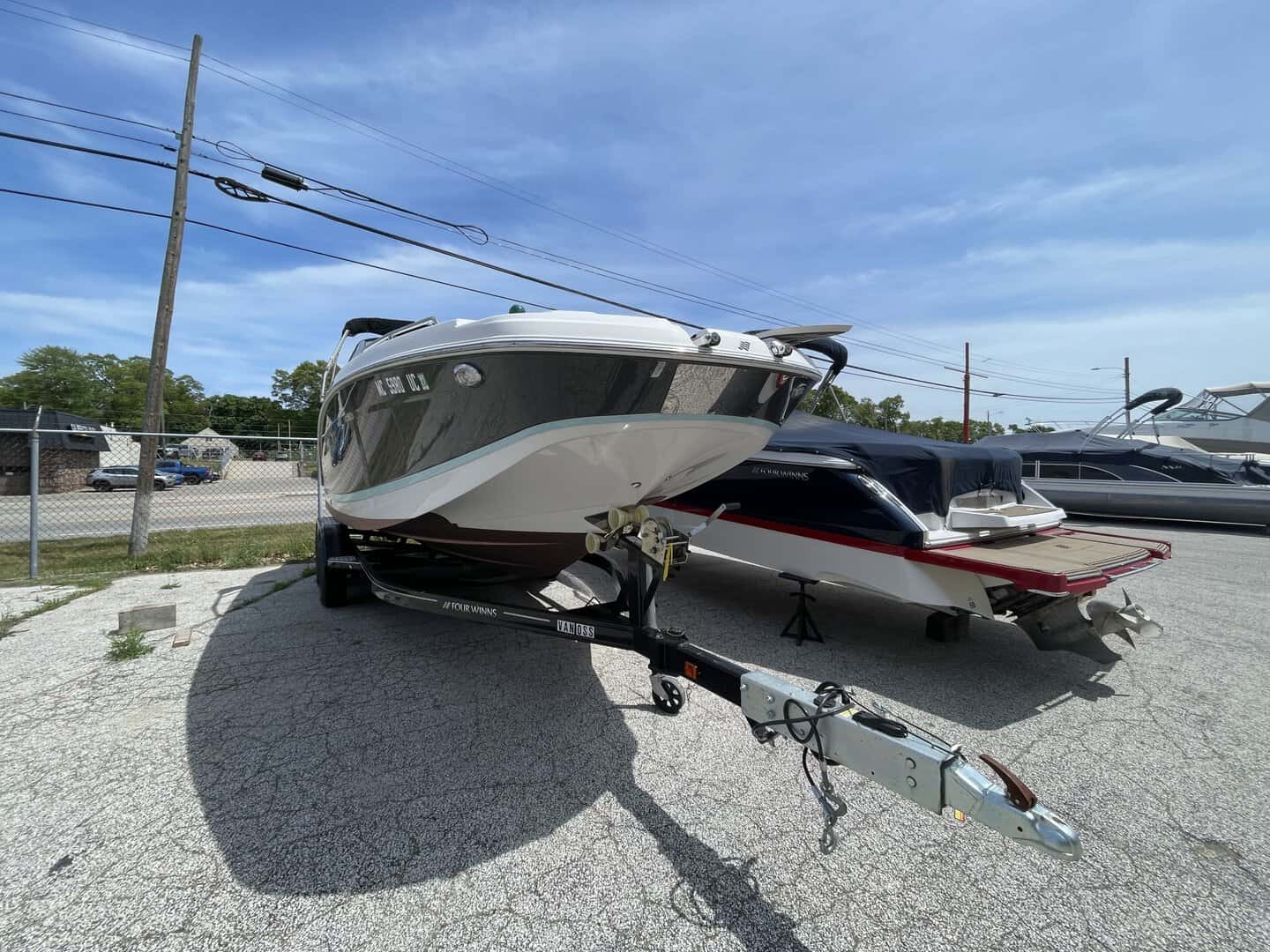 A sleek white and black boat on a trailer at Hall's Sport Center, ready for water adventures.