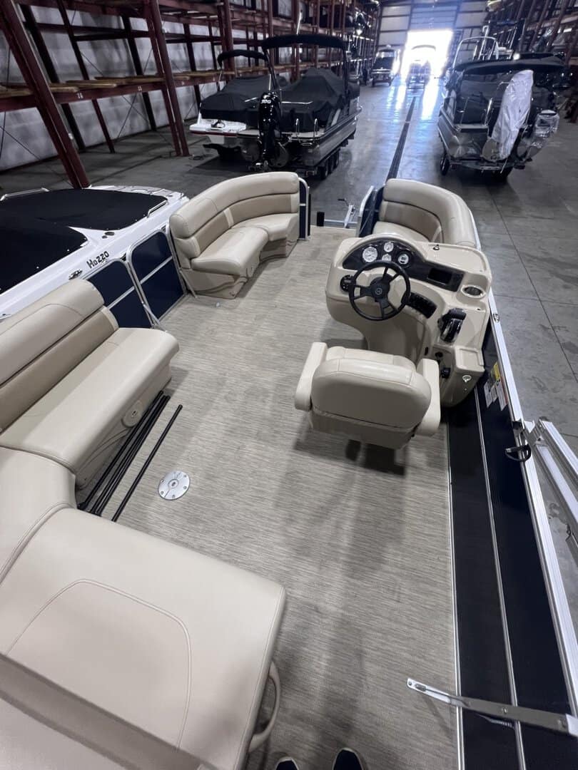 Pontoon boat interior with comfortable beige seating and steering console, ideal for recreational bo.