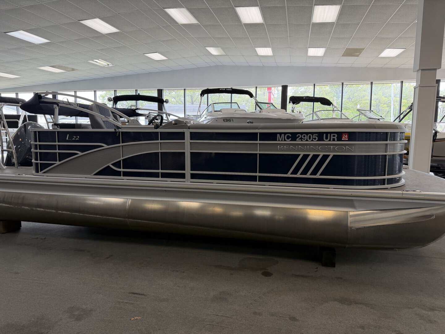 Pontoon boat displayed indoors at Hall's Sport Center, perfect for lakes and family outings.
